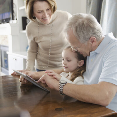 Grandparents assisting granddaughter with pc tablet